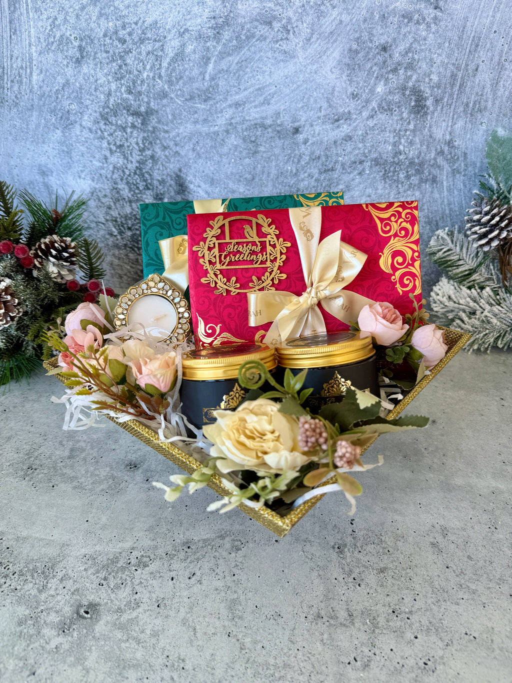 Sparkle holiday hamper with gift boxes, two snack jars, flowers and a tealight holder on a gold tray.